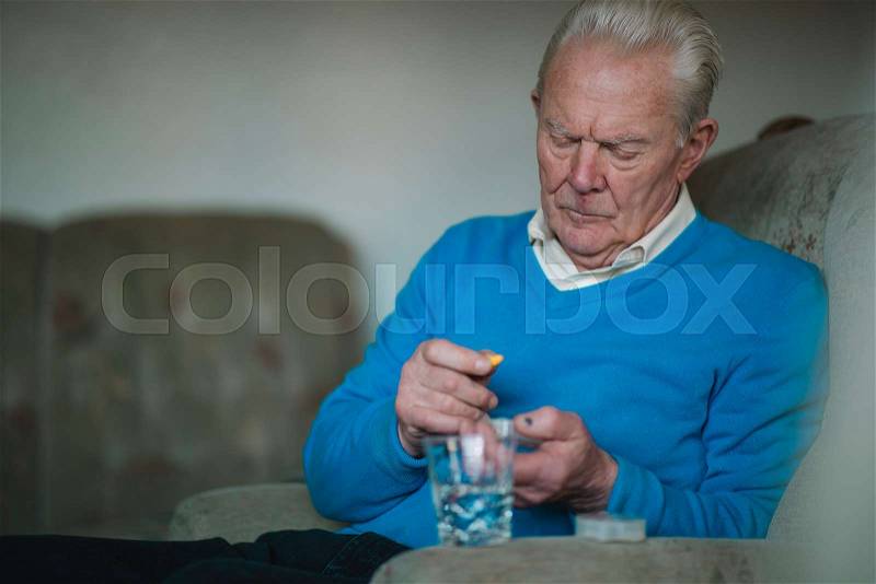 Senior man is taking his medication and vitamins at home. , stock photo