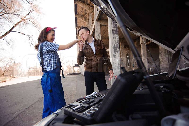 Professional auto woman mechanic and man repair auto outdoors, stock photo
