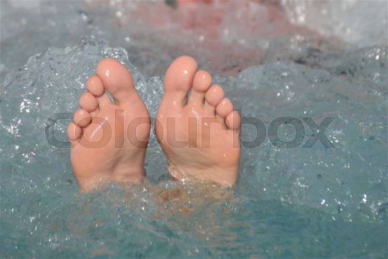 Female bare feet out of bubbling water in a whirlpool outdoors in summertime in vacation, stock photo