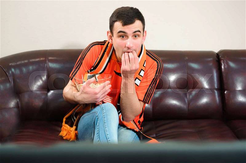 Man watching football, football fan on the sofa, stock photo