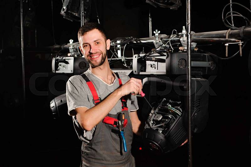 The lighting engineer repairs the light device on stage, stock photo