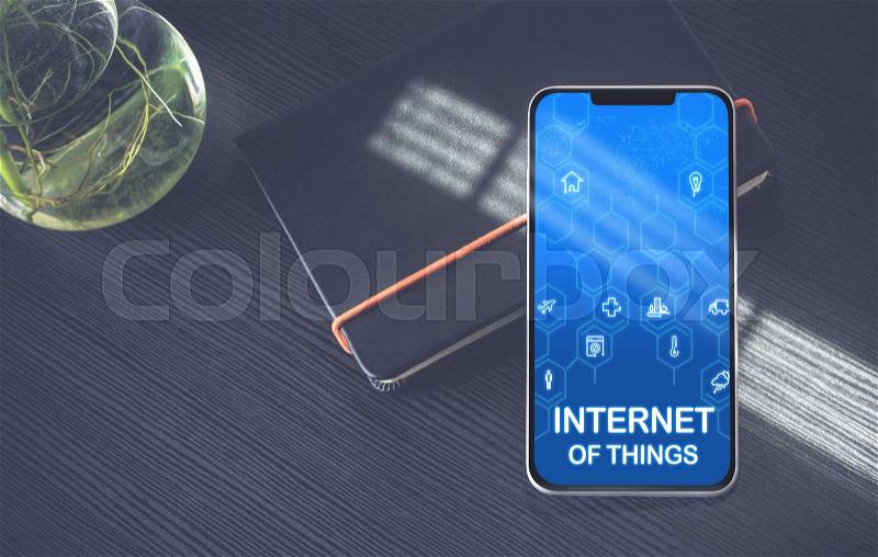 Internet of things (IoT) features icons on mobile phone screen lay on black notebook near window with sunlight on black wooden desk,Digital age technology concept, stock photo