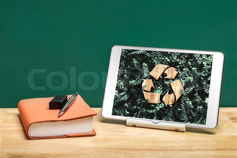 Recycle sign on green leaf on tablet app at office desk with book and pencil..enviroment eco system concept, stock photo