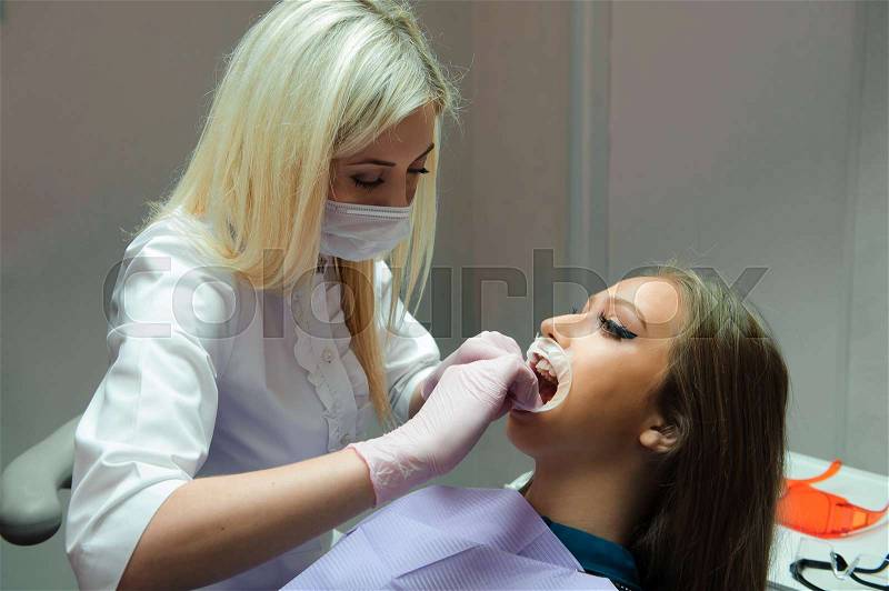 Female dentists treating patient in the clinic, stock photo