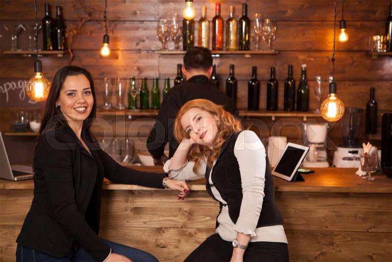 Two young beautiful women talking in the pub. Having fun in a hipster pub, stock photo