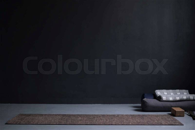 Gym interior with yoga mat and props. no people. Copy space on black wall at studio, stock photo