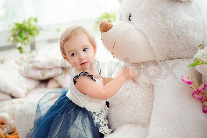 Beautiful little girl with toy smiling at the camera, stock photo