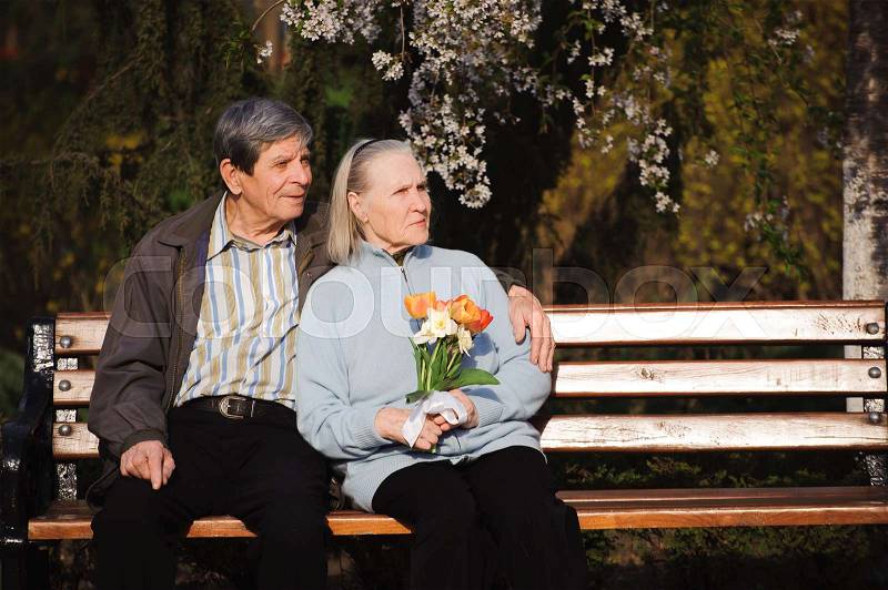 Beautiful happy old people sitting in the autumn park, stock photo