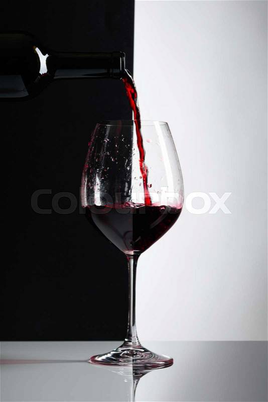 Red wine is poured into a glass. Reflexive background, copy space for your text, stock photo