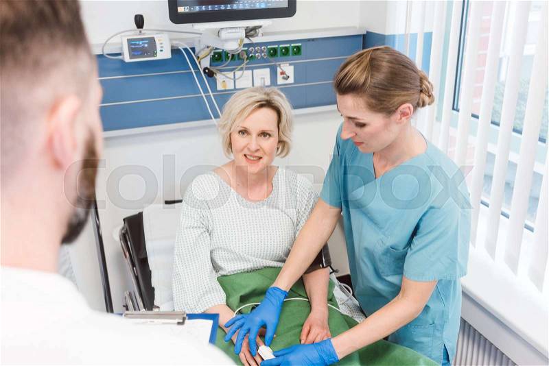 Patient in recovery room of hospital talking to doctor and nurse , stock photo
