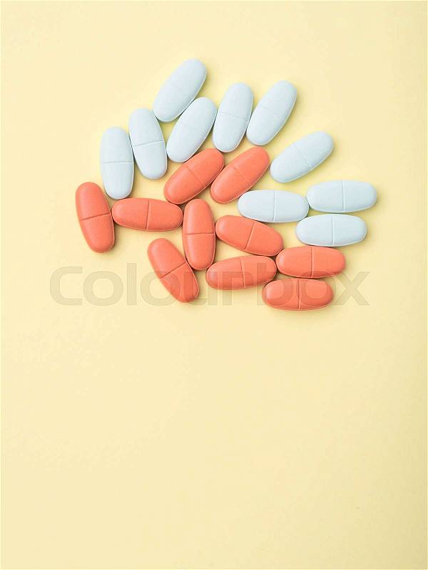 Blue and red pills on yellow background. Dietary supplements concept. Flat lay, stock photo