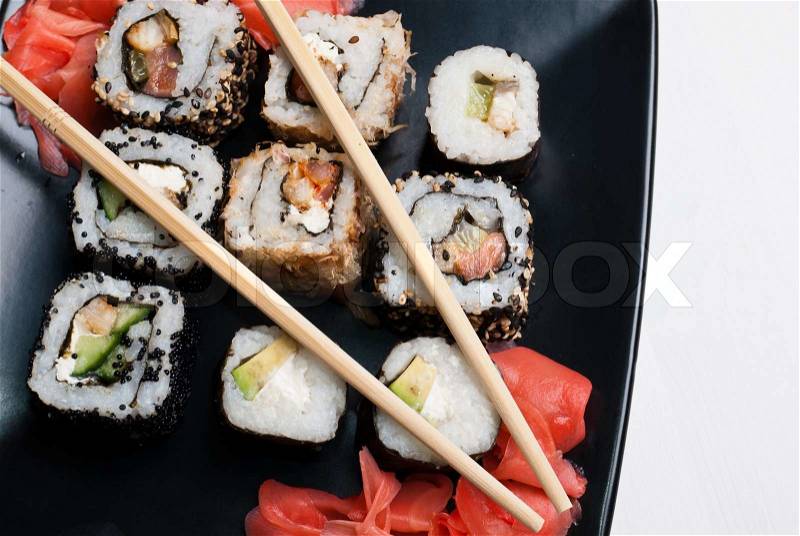 Sushi on a black plate on white table, stock photo