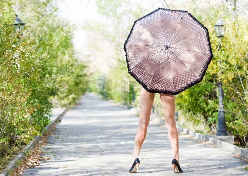 Lady on high heels with umbrella in autumn park, stock photo