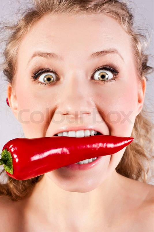 Beautiful woman teeth eating red hot chili pepper, stock photo