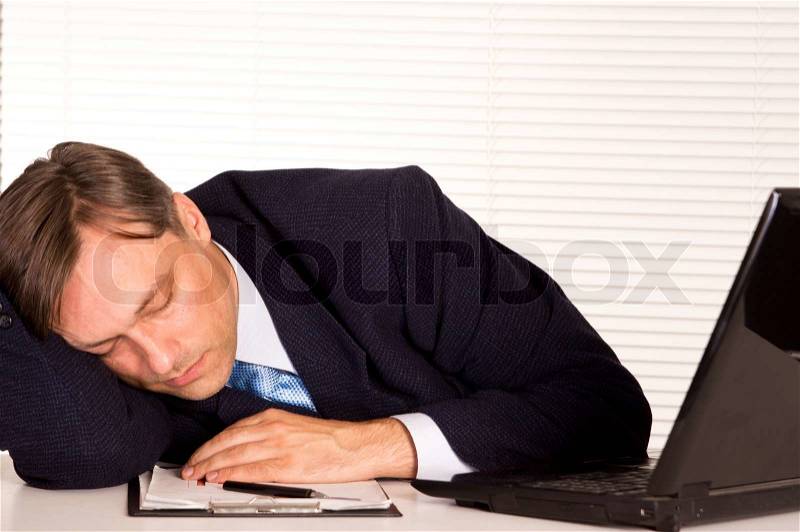 Businessman sleeping at office, stock photo