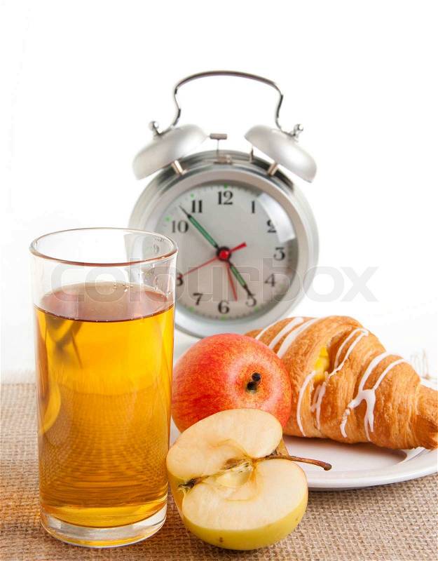 Juice, croissant and apple for a breakfast, an alarm clock, stock photo