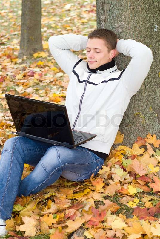 Guy with laptop at tree, stock photo