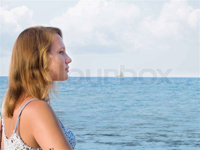 Girl looks far ahead at the evening sea, stock photo