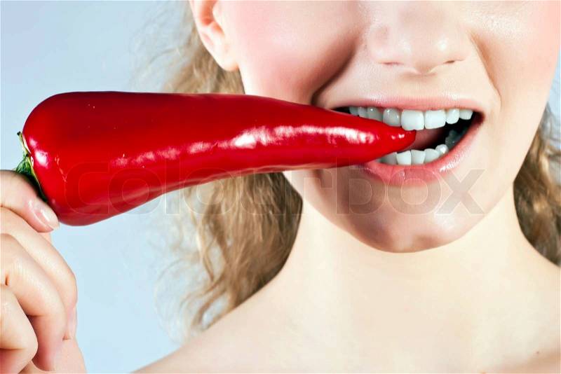 Beautiful woman teeth eating red hot chili pepper, stock photo