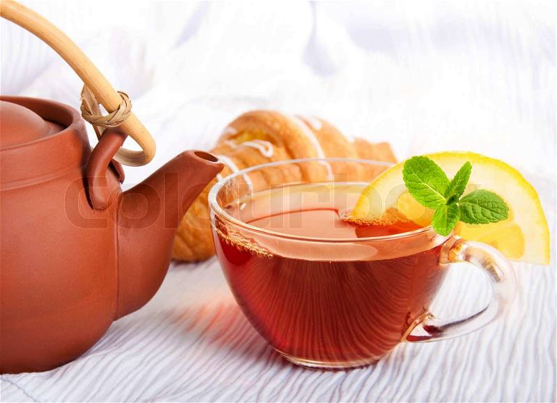 Cup of fragrant tea flowing from a ceramic teapot, stock photo