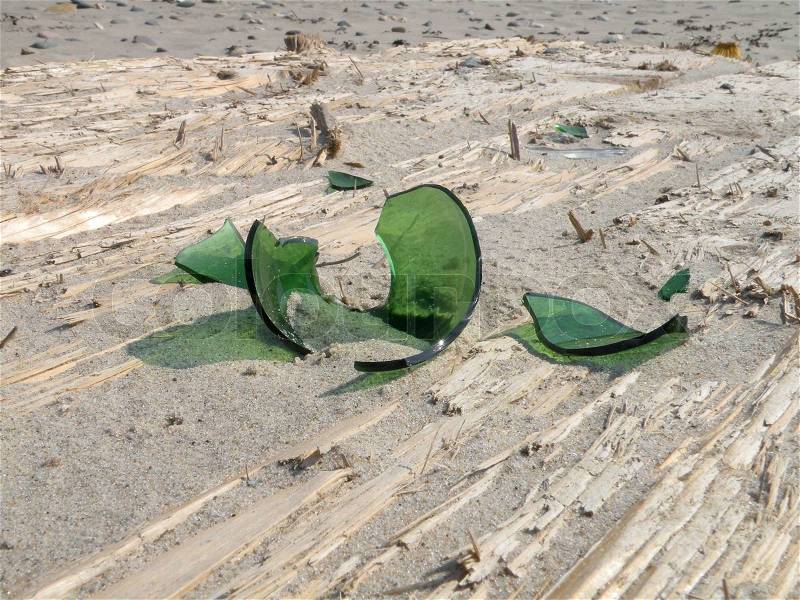 Special perspective of some green glass pieces on wood at beach, stock photo