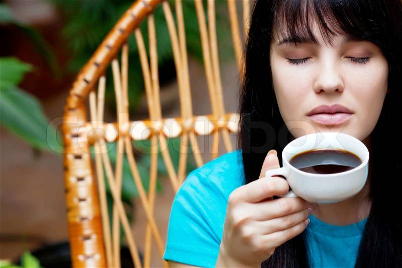 Girl with cup of coffee in garden, stock photo