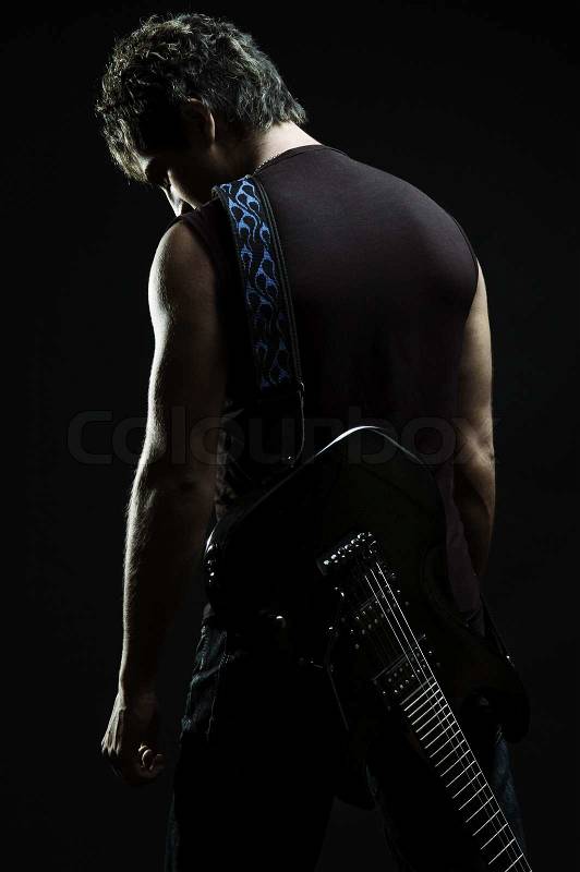 Man with guitar in the darkness, stock photo