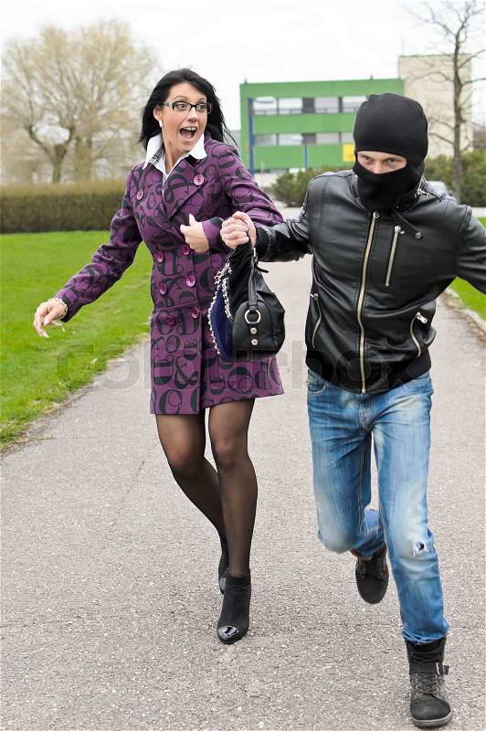 Daylight robbery on the street Thief steals a bag, stock photo