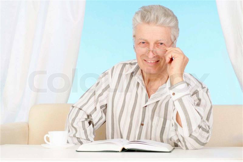 Beautiful old Caucasian man with book sits, stock photo