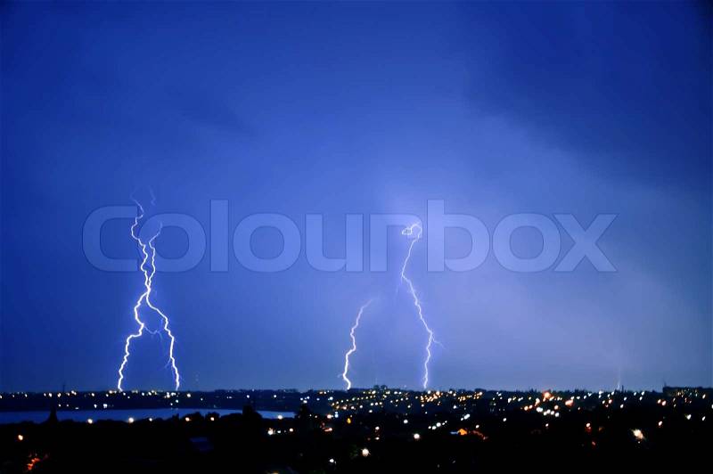 Lightning strike over dark blue sky in night city, stock photo