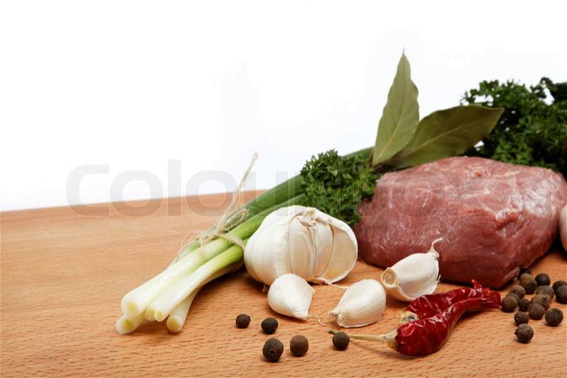 Raw meat, vegetables and spices isolated on a wooden table, stock photo