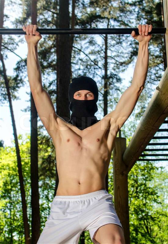 Antiglobalist trains, pull-ups on a bar in a forest, stock photo