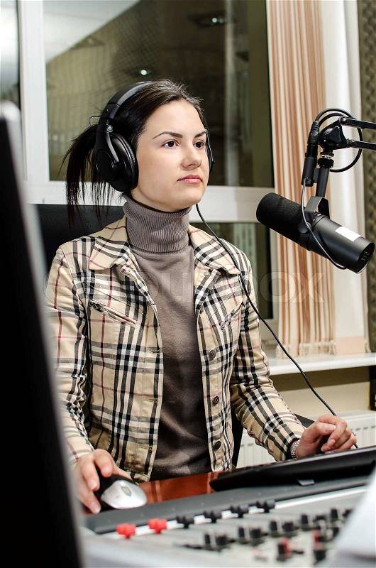 Anchorwoman sitting in front of a microphone on the radio, stock photo
