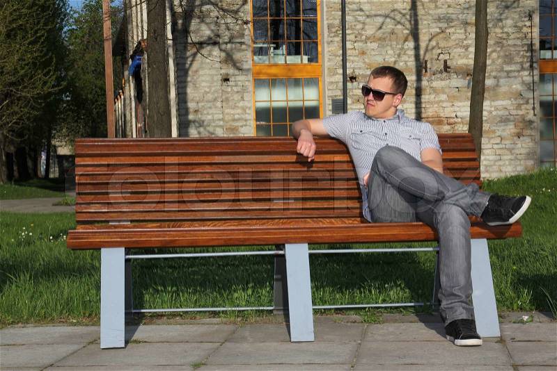 Man sitting in park on the bench, stock photo