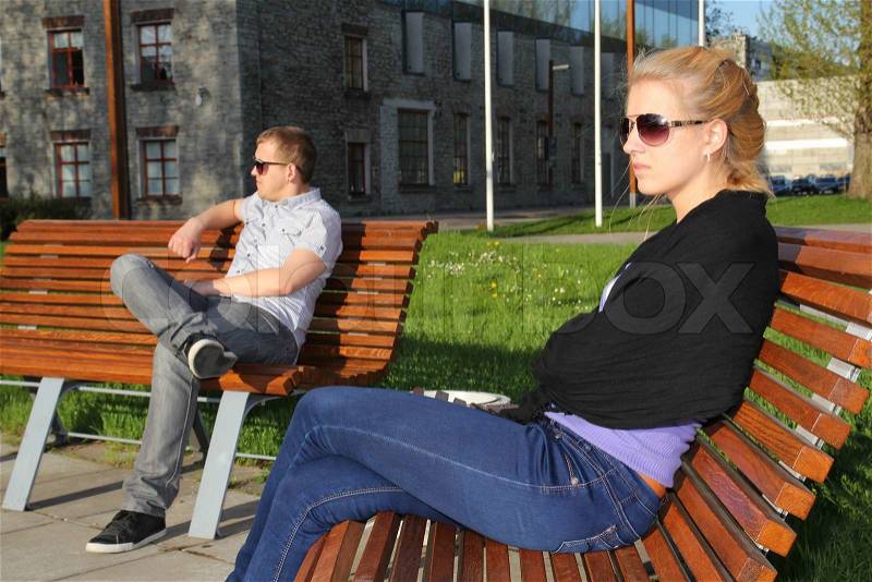 Sad young couple sitting in park, stock photo