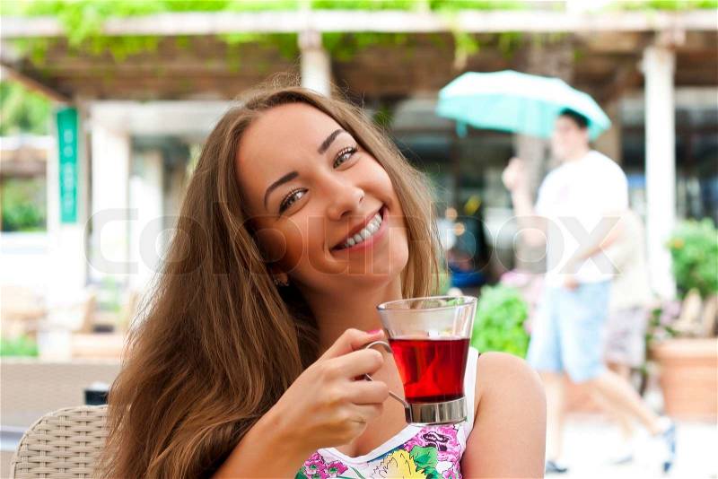 Young woman drinking tea in a cafe outdoors, stock photo