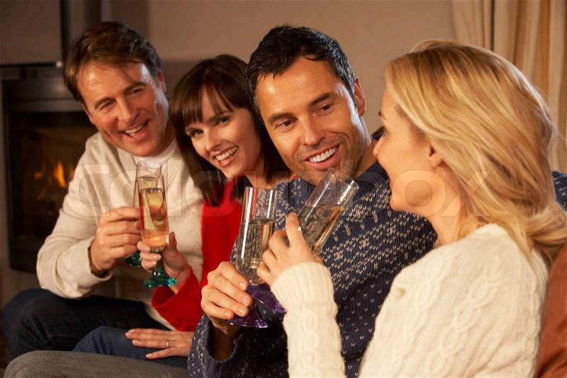 Group Of Middle Aged Couples Sitting On Sofa With Champagne, stock photo