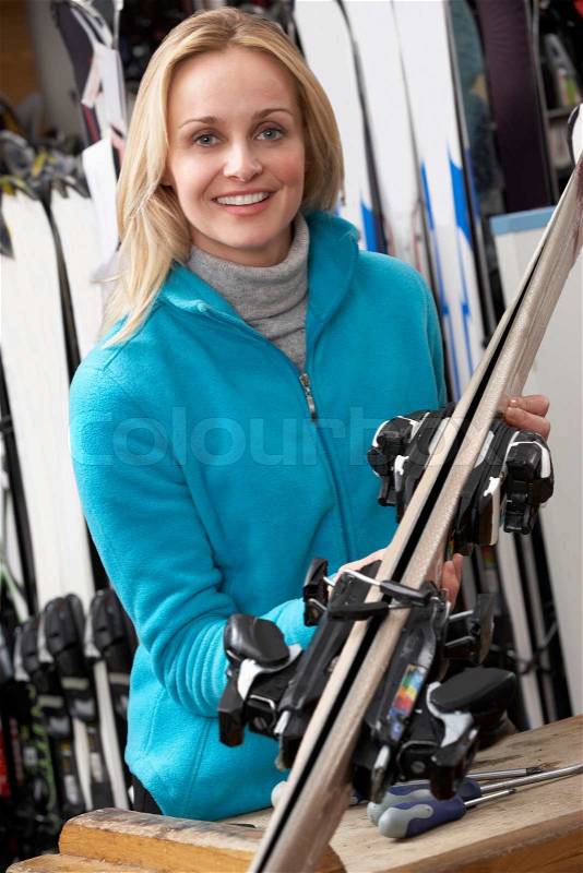 Female Sales Assistant With Skis In Hire Shop, stock photo
