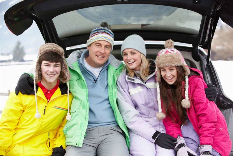 Teenage Family Sitting In Boot Of Car Wearing Winter Clothes, stock photo