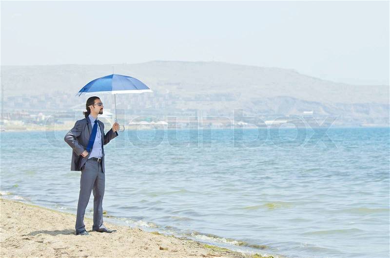 Man with umbrella on seaside beach, stock photo