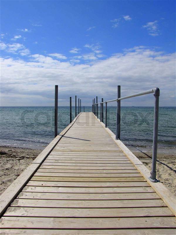 A wooden jetty goes into the beautiful blue sea, stock photo