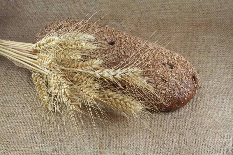 Bread and wheat on a coarse cloth, stock photo