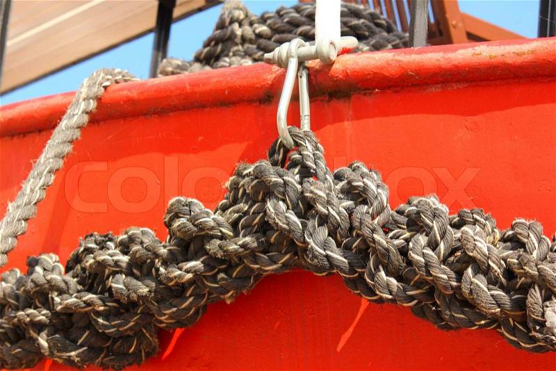 Close-up of an old frayed boat rope, on a red boat, stock photo