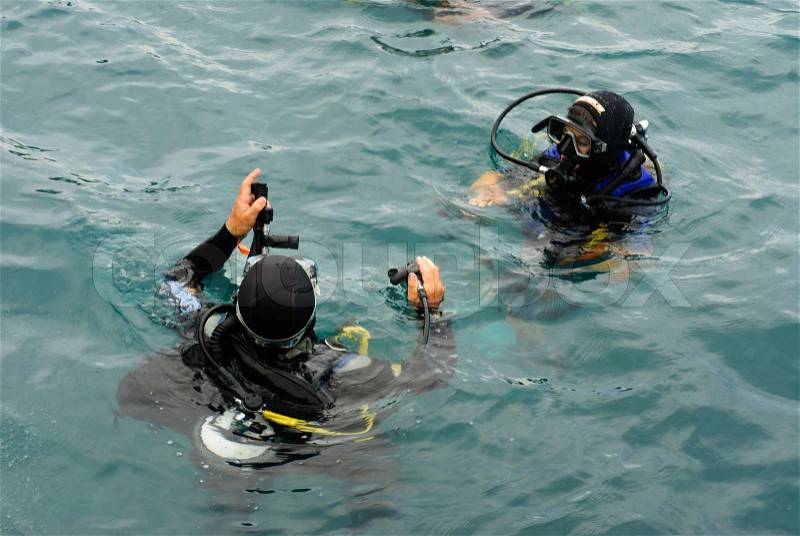 Scuba divers scuba dive in sea, stock photo