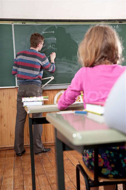 Young male teacher explaning math to the elementary age pupils at school, stock photo