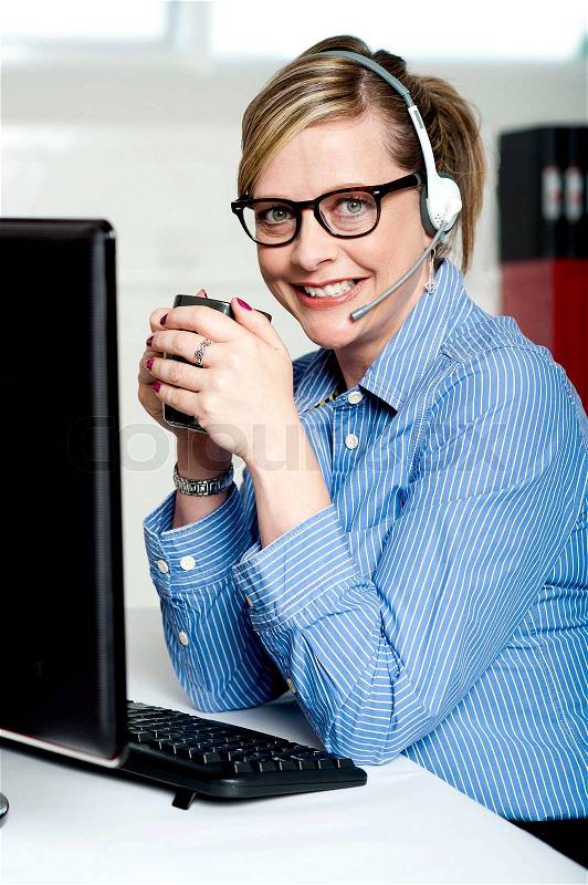 Help desk executive drinking coffee at work, stock photo