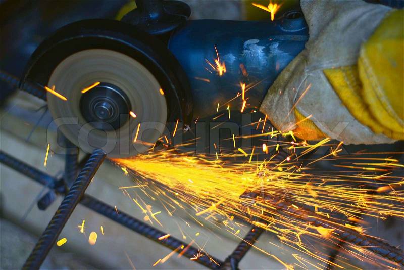Worker cutting metal with many sharp sparks, stock photo