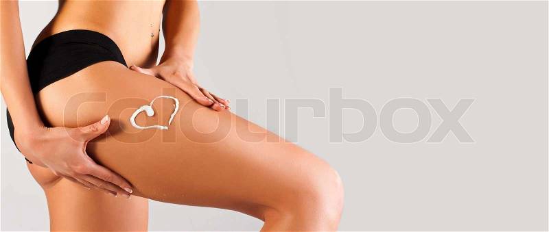 Woman applying moisturizer cream on legs, stock photo