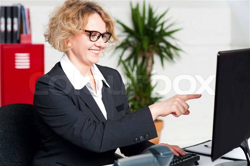 Cheerful woman pointing at computer screen, stock photo