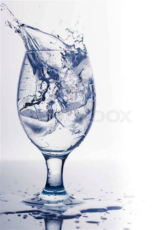 Splash from ice cube in a glass of water, isolated on the white background, stock photo